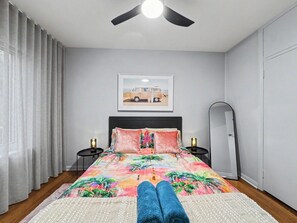 A bedroom with a bed, a ceiling fan, a nightstand, a mirror, and a framed picture on the wall. - Ground floor one bedroom apartment in South Yarra (South Yarra)