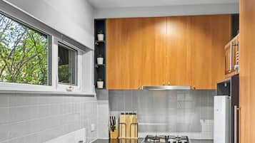Una cocina moderna con armarios de madera, estufa a gas, pileta y ventana.