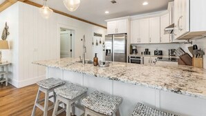 A kitchen with white cabinets, a large island with stools, stainless steel appliances, and pendant lighting. - Walk to Beach & Dining, Luxury Home in Seagrove, Private Pool, Sleeps 14, Bikes (Santa Rosa Beach)