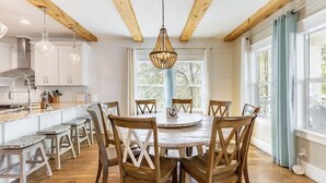A kitchen with wooden beams, white cabinets, a round dining table with wooden chairs, and pendant lighting. - Walk to Beach & Dining, Luxury Home in Seagrove, Private Pool, Sleeps 14, Bikes (Santa Rosa Beach)