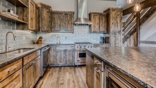 A kitchen with wooden cabinets, a stainless steel range hood, a built-in oven, and a granite countertop. - Whitefish Mountain Escape, 6 Bedroom Sleeps 14, Amazing Views! (Whitefish)