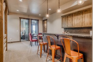 A kitchen with wooden cabinets, a bar area with stools, and a view into the dining area.