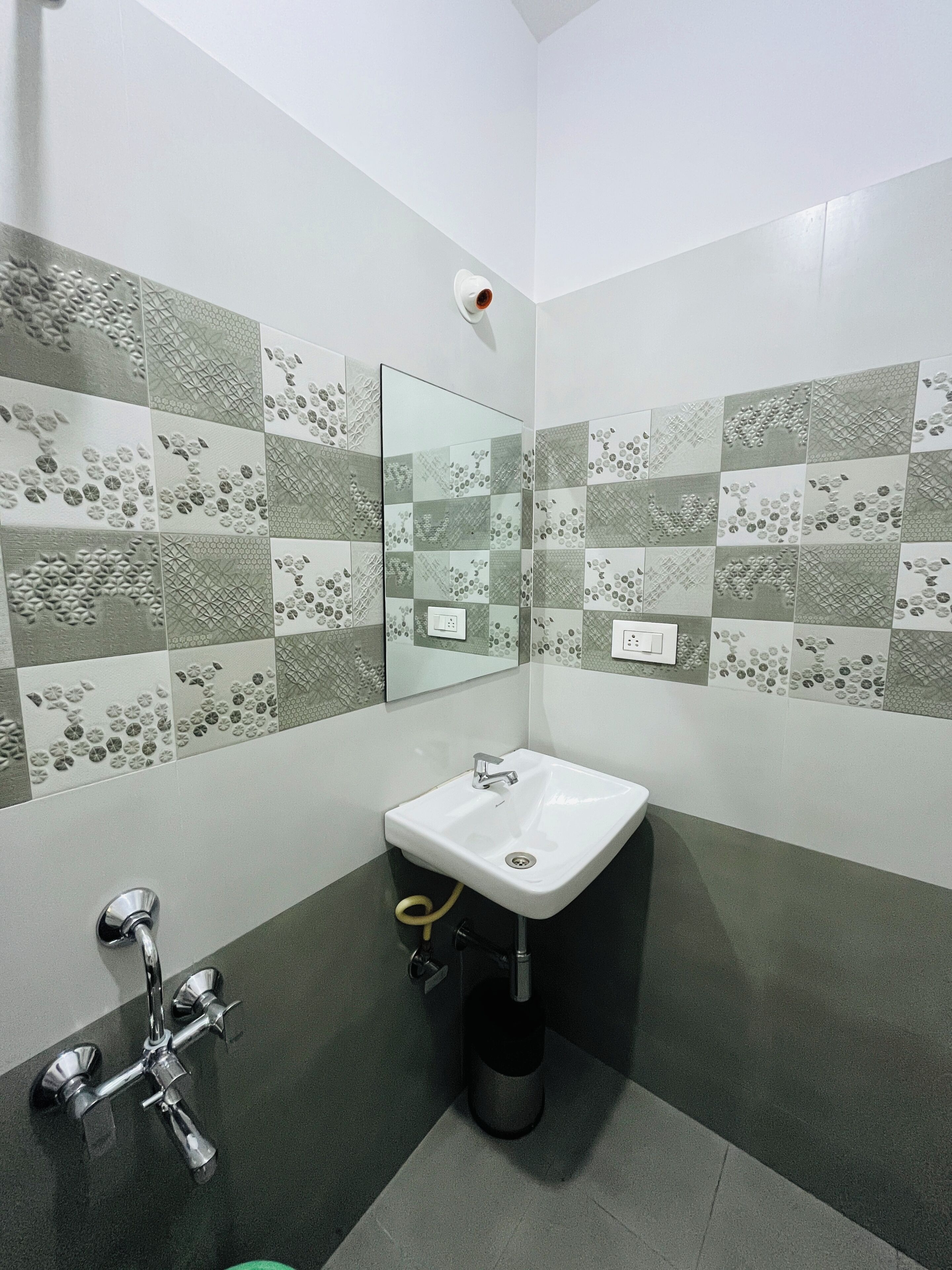 A bathroom with a white sink, a mirror, and a shower with a chrome faucet.