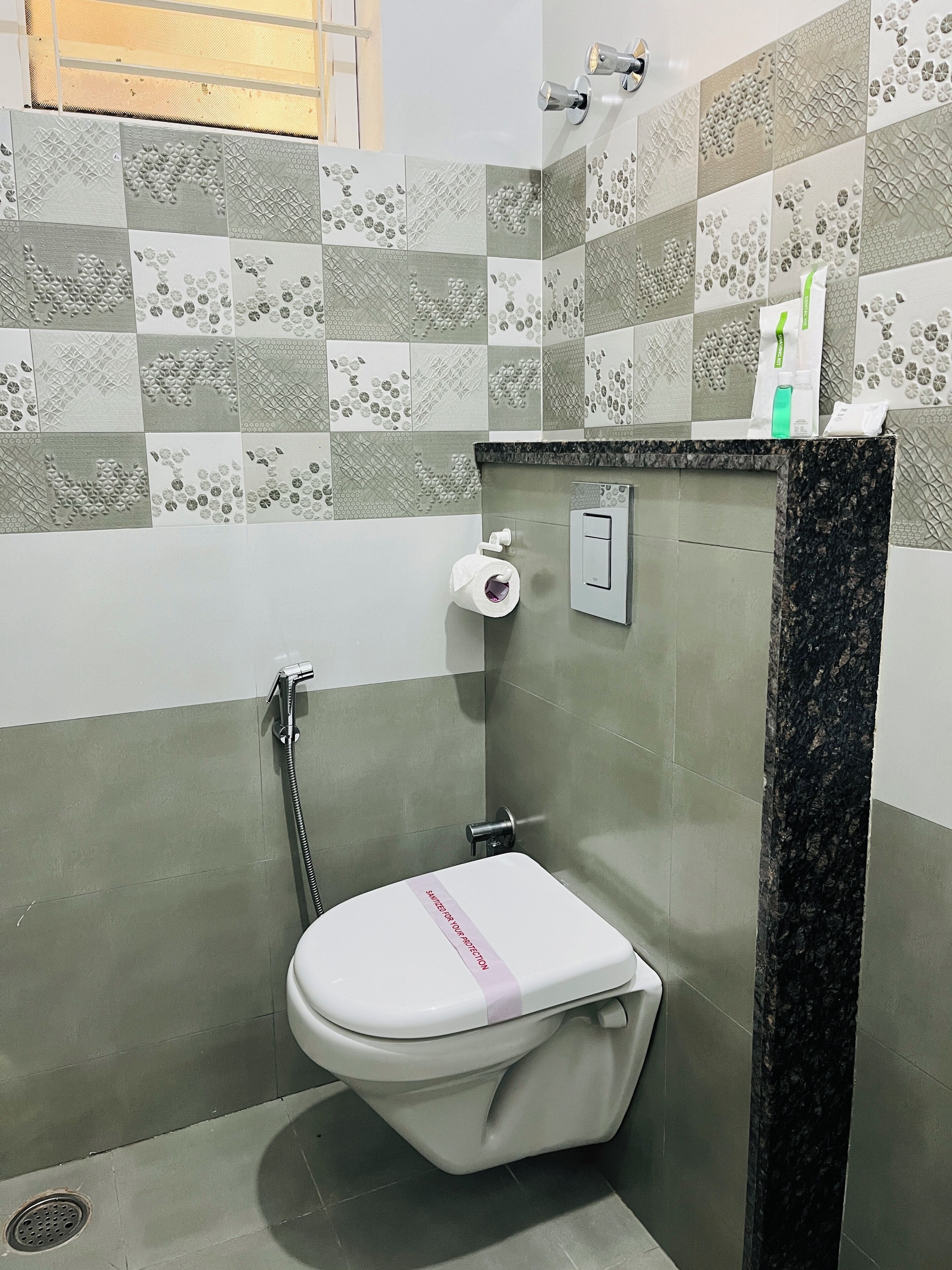 A bathroom with a toilet, a shower, and a towel dispenser.