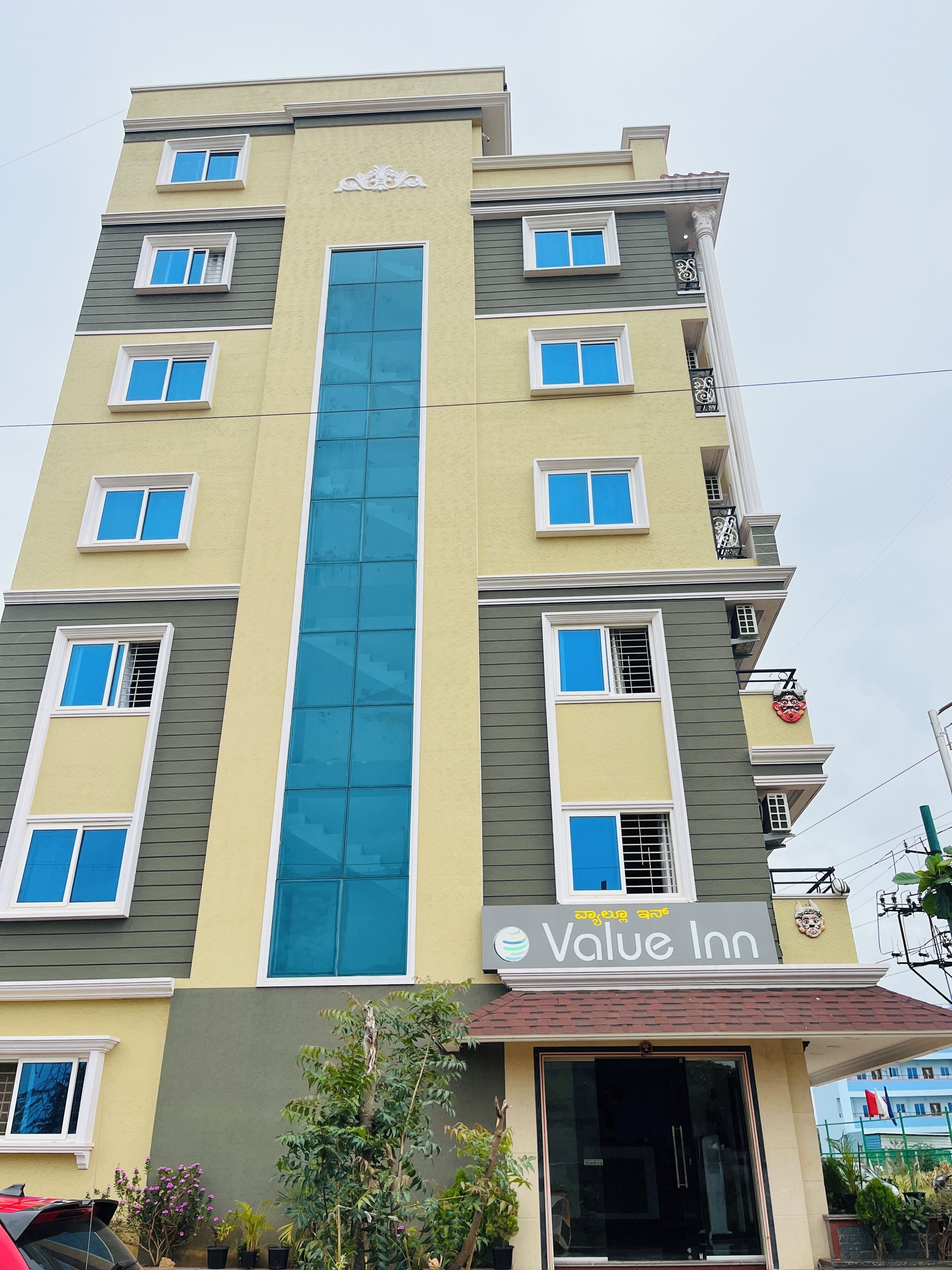 A multi-story hotel with a central blue glass facade, multiple balconies, and a sign for 'Volue Inn'.
