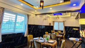 Un restaurante con paredes de mármol, muebles de madera y un techo con iluminación empotrada y un candelabro.
