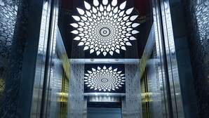 Un ascensor con un diseño geométrico en el techo y una alfombra roja en el suelo.