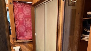 A compact, wood-paneled bathroom with a toilet, a towel rack, and a roll of toilet paper.