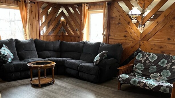 A cozy living room with a sectional sofa, a floral-patterned chair, and a small wooden table.