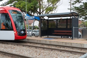 Un quai de gare doté d’un abri et d’un panneau indiquant la direction de Glenelg East.