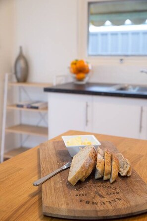 Ein Schneidebrett mit Brot und einer kleinen Schale Butter auf einer Küchenarbeitsplatte.