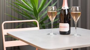Eine Terrasse mit Tisch, zwei Stühlen, einer Weinflasche und zwei Weingläsern.