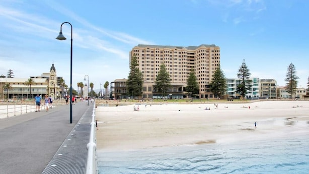 Eine Uferpromenade mit einem Hochhaus, einer Promenade und einem Sandstrand.