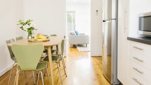 A modern kitchen with a dining area, wooden flooring, and a view to an outdoor seating area. - 2 BR Apt | Free Parking & Wi-Fi Near Glenelg Beach (Glenelg East)