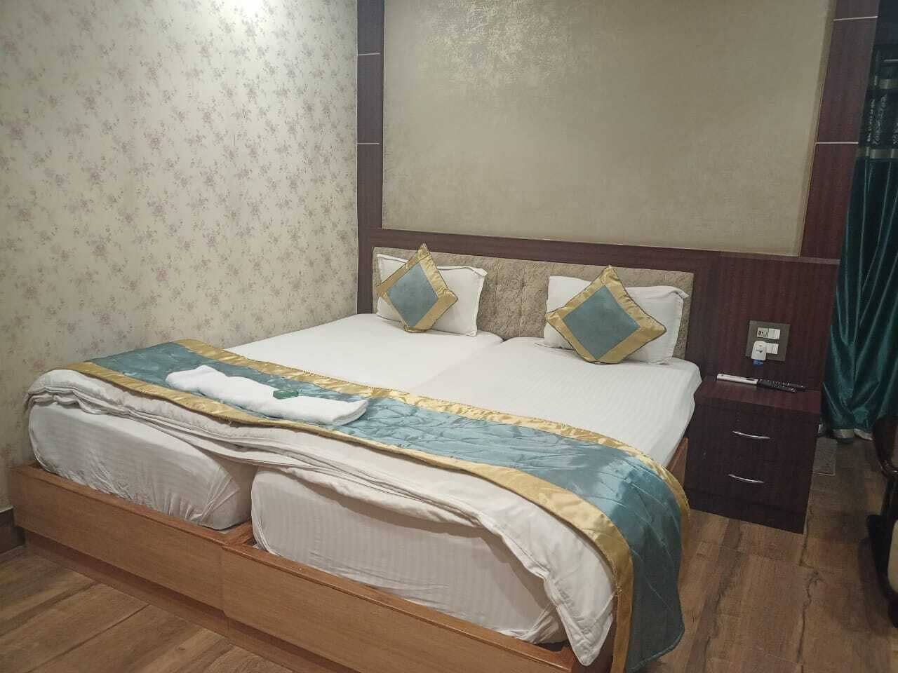 Een keurig opgemaakt bed met een blauw-witte spreideken, een houten hoofdbord en een nachtkastje met een lamp.