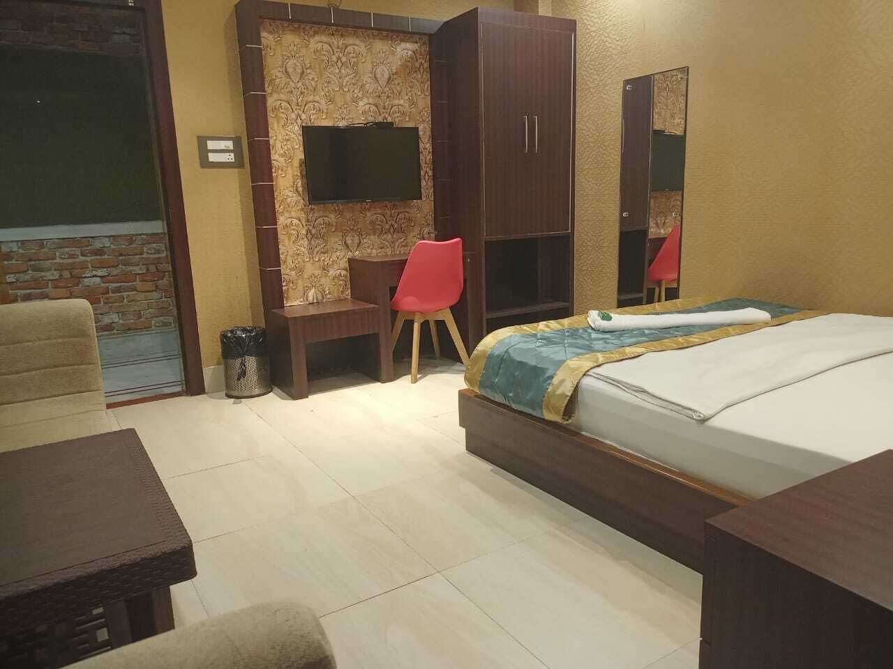 Una camera d'albergo con un letto, una scrivania, una sedia, una TV e un armadio.