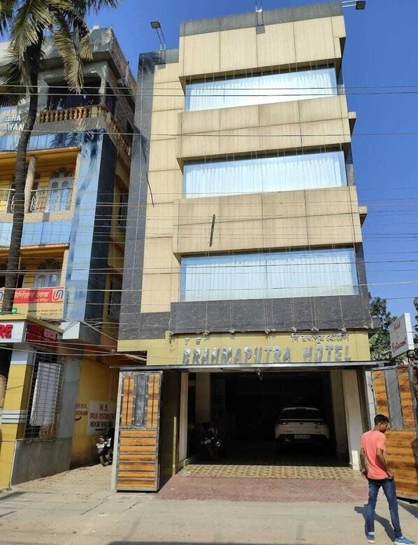 A hotel with multiple floors, a visible entrance, and a parked car in front. - The Brahmaputra Hotel (Dhubri)