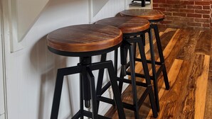 Une cuisine avec un mur en briques, un plafond en bois et un coin bar avec des tabourets.