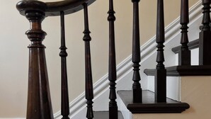 Un escalier en bois avec une rampe courbée et des balustres sombres.