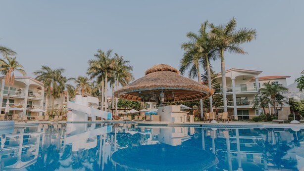 A resort pool area with a central gazebo, palm trees, and a reflection pool. - Hermoso Depa en la Mejor Zona y Amenidades Únicas (Acapulco de Juárez)