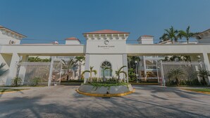 A hotel entrance with a gated driveway, palm trees, and a clear blue sky. - Hermoso Depa en la Mejor Zona y Amenidades Únicas (Acapulco de Juárez)