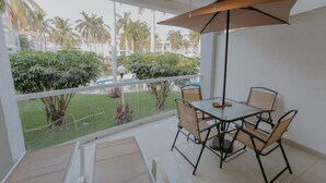 A balcony with a glass railing, a table with chairs, and a ceiling fan. - Hermoso Depa en la Mejor Zona y Amenidades Únicas (Acapulco de Juárez)