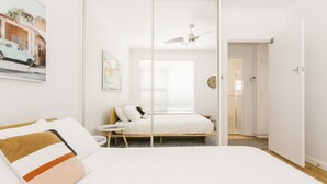 A bedroom with a bed, bedside table, and a ceiling fan.