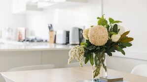 A table with a vase of flowers and a stack of magazines.