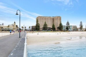 Un paseo marítimo con playa, un hotel de gran altura y una senda peatonal.