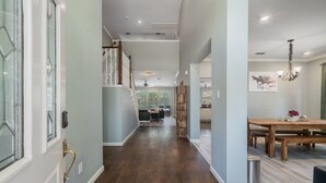 Un hall d’entrée spacieux avec un plancher en bois, un coin repas avec une table et des bancs en bois, et un escalier menant à l’étage supérieur.