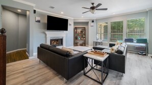 Un salon doté d’une cheminée, d’un ventilateur de plafond et d’un grand téléviseur.