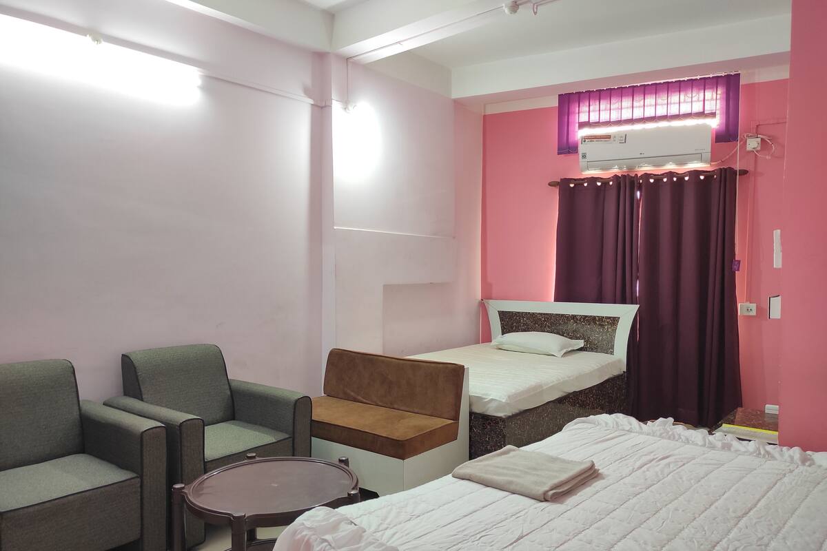 A room with a bed, a chair, a small table, and a window with curtains.
