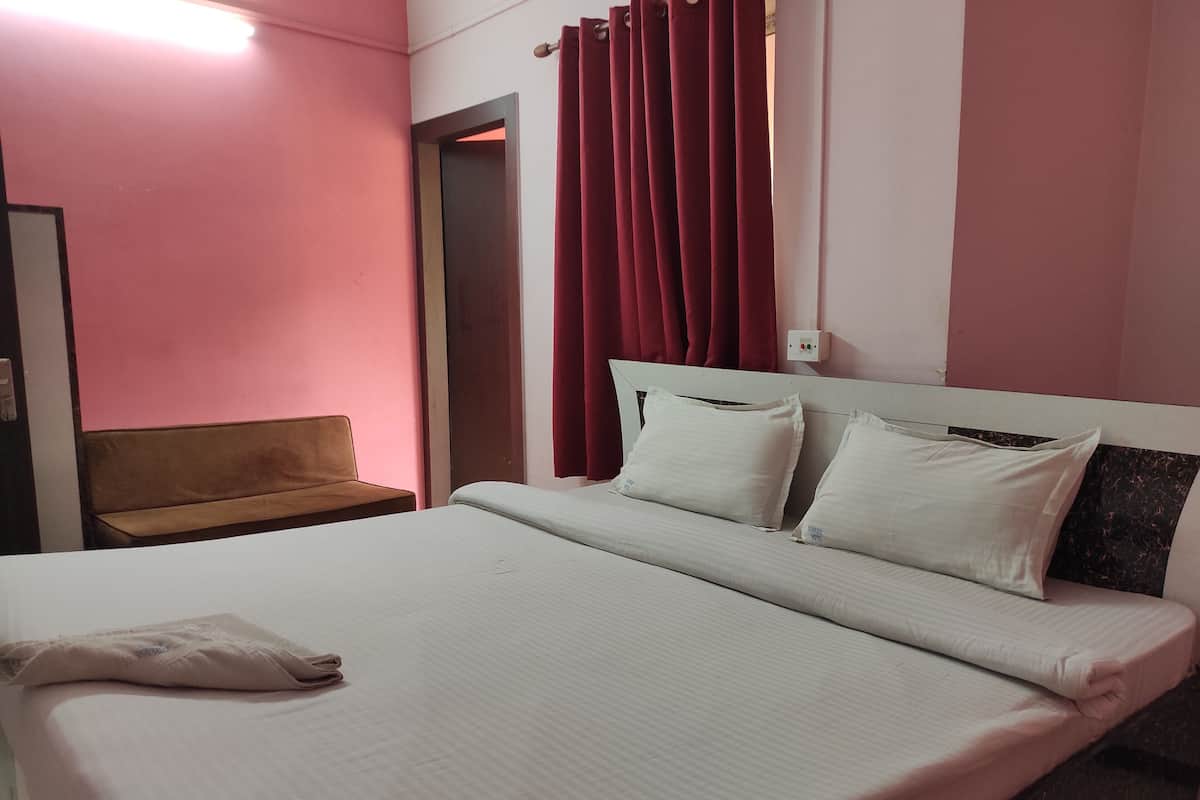 A bed with white bedding, a brown bench, and red curtains.