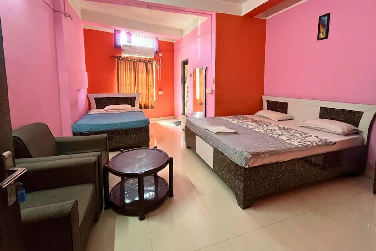 A hotel room with two beds, a small table, and a chair.