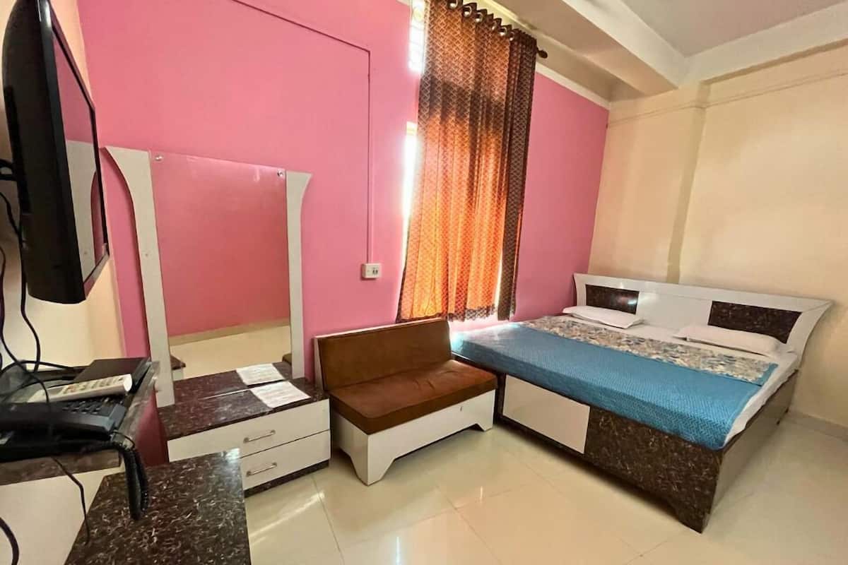 A bedroom with a bed, a desk, a chair, and a TV.