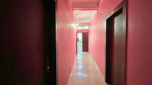 Un pasillo largo y estrecho con paredes rosadas y suelo blanco.