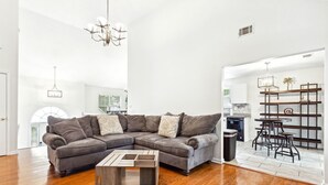 Una sala de estar amplia con un sofá modular, una mesa de centro y un comedor con mesa y sillas.