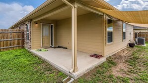 Een gelijkvloers huis met een overdekte veranda, een bakstenen gevel en een omheinde achtertuin.