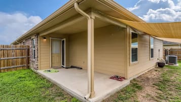 Une maison de plain-pied dotée d’un porche couvert, d’une façade en briques et d’un jardin clôturé.