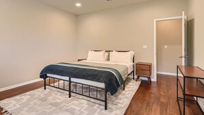 Een slaapkamer met een bed, nachtkastjes, een bankje en een deur.