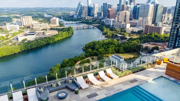 A rooftop pool area with lounge chairs and a view of a city skyline and river. - Modern Downtown Condo*Rooftop pool*Top Amenities (Austin)