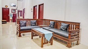 A living room with a wooden sofa set, a coffee table, and a water dispenser. - OYO LIFE 92034 Jay Homestay Syariah (Bandar Lampung)