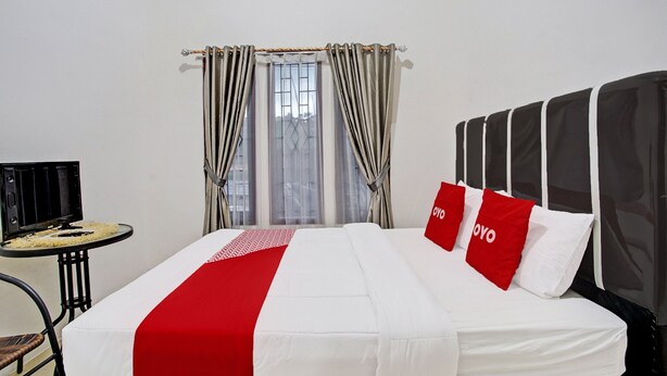 A hotel room with a bed, a small table, and a chair. - OYO LIFE 92034 Jay Homestay Syariah (Bandar Lampung)