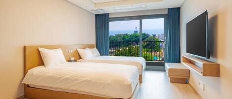 A hotel room with a large bed, a TV, and a balcony with a city view.