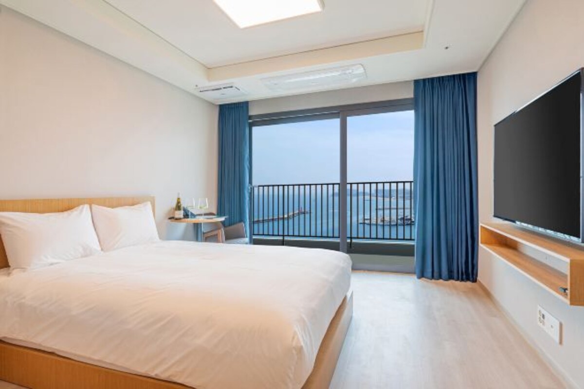 Une chambre d’hôtel avec un lit, une télévision, un balcon avec vue et une fenêtre.