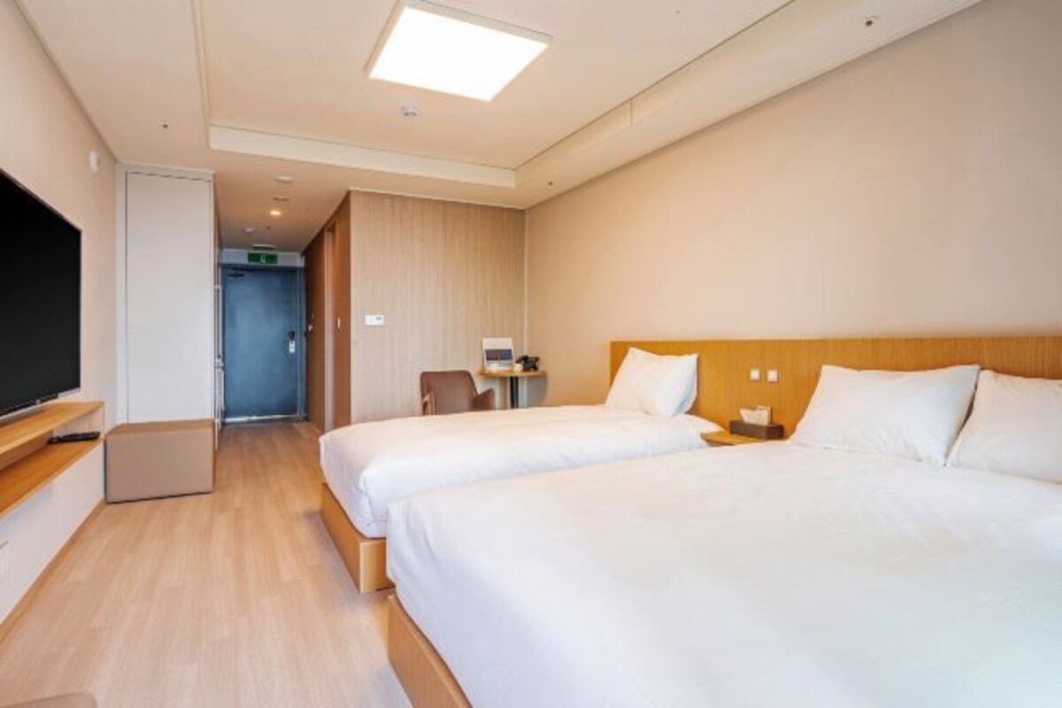 Une chambre d’hôtel avec deux lits, une télévision, un bureau et une chaise.