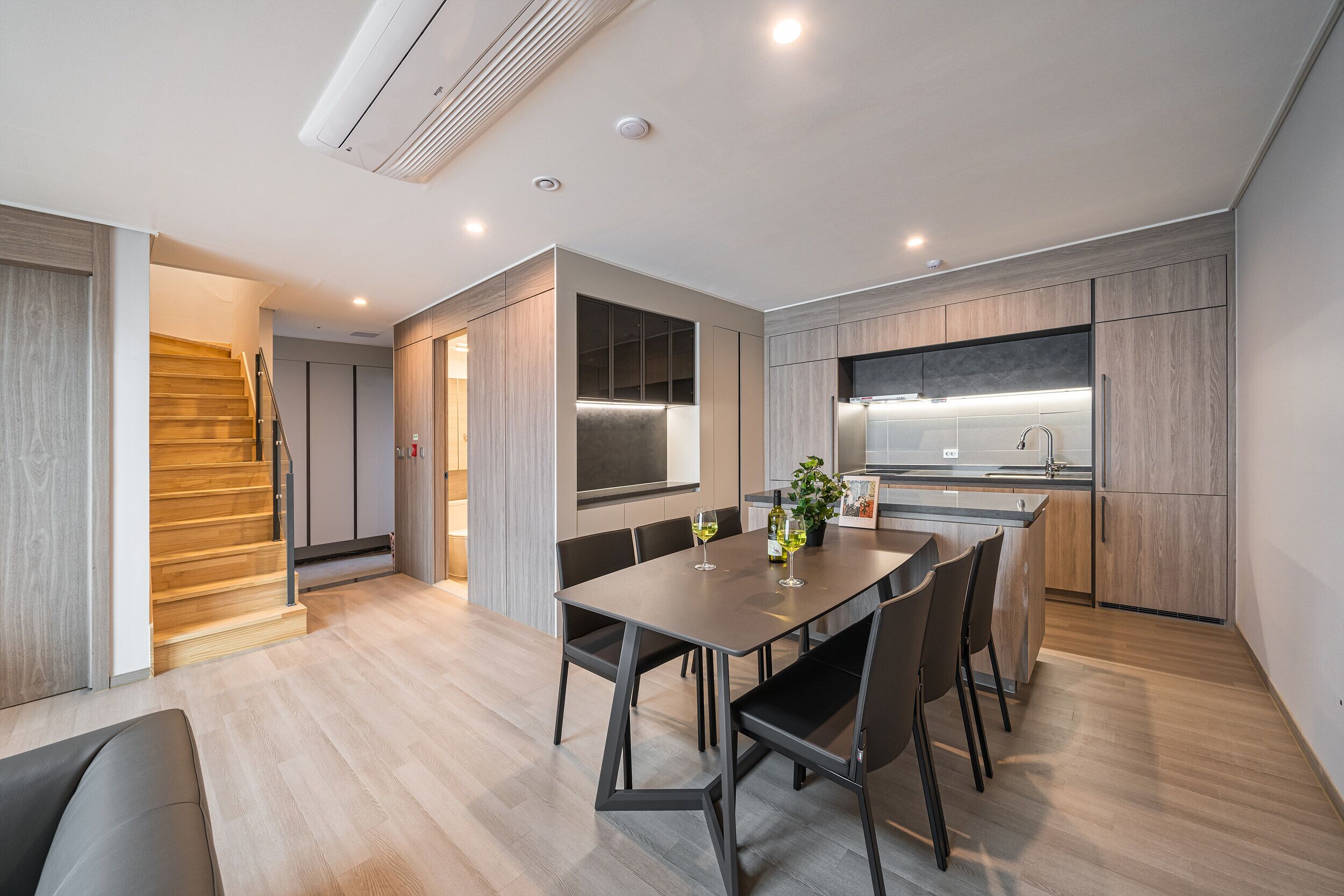 Une cuisine moderne avec un coin repas, un plancher en bois et des placards intégrés.