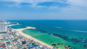Vista aérea de una ciudad costera con playa, aguas azules cristalinas y edificios a lo largo de la costa.