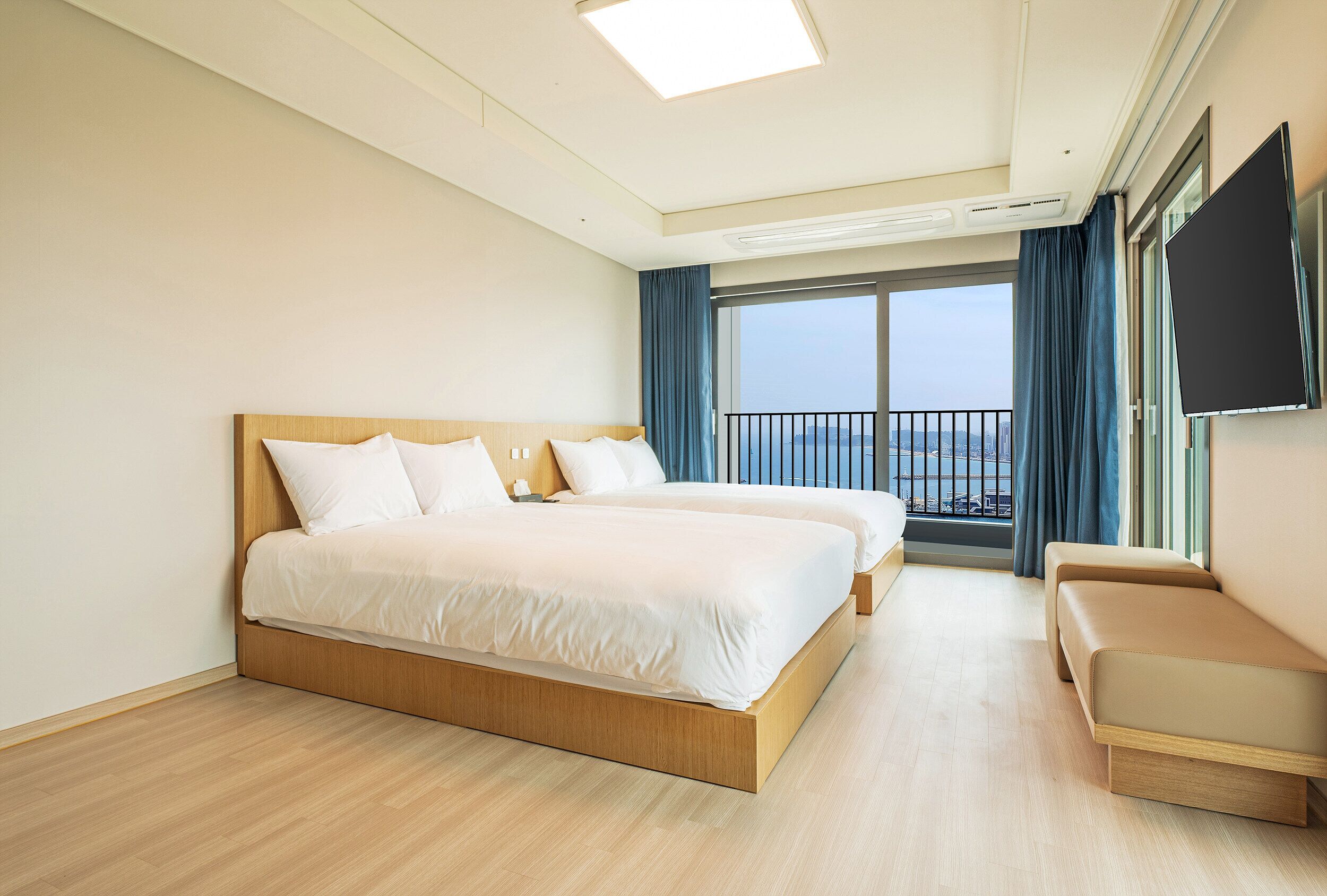A hotel room with a large bed, a sofa, a TV, and a balcony with a view.