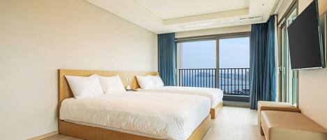 A hotel room with a large bed, a sofa, a TV, and a balcony with a view.